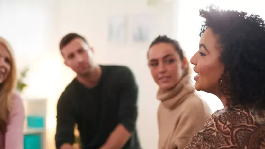 Eine Frau spricht mit einer Runde von Menschen. 